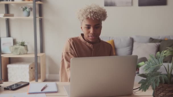 Afro-Frau setzt Kopfhörer auf und startet Online-Anruf per Laptop mit befreundetem Studenten — Stockvideo