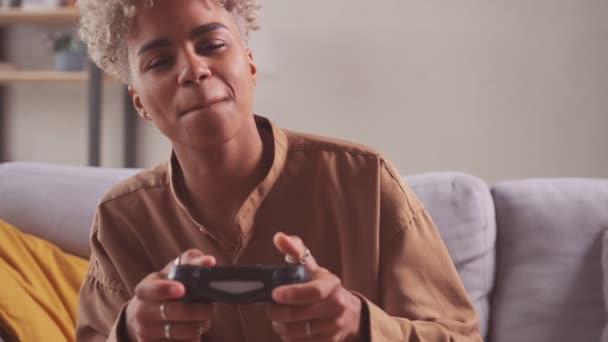 Africano mulher jogador sentar no sofá cruz perna em casa segurando console jogo pad — Vídeo de Stock