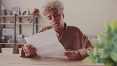 Üzgün Afro kadın kötü haber okuyan zarfı açtı. Kağıttan posta aldı.