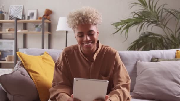 Afrikaanse vrouw zitten op de bank praten met familie op afstand met behulp van tablet — Stockvideo