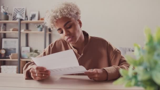 Mujer africana leyendo carta de papel sintiéndose emocionada de recibir buenas noticias — Vídeos de Stock