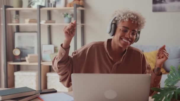 Feliz dama africana con auriculares inalámbricos escuchando música distraída del trabajo — Vídeos de Stock