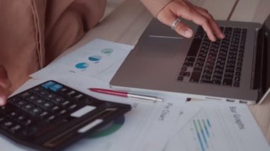 Kapanış muhasebecisi hesap makinesi ve dizüstü bilgisayar kullanarak finansal hesaplarla çalışıyor.