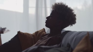 Huzurlu, huzurlu, rahat kanepeye yaslanmış genç bir Afrikalı kadın.