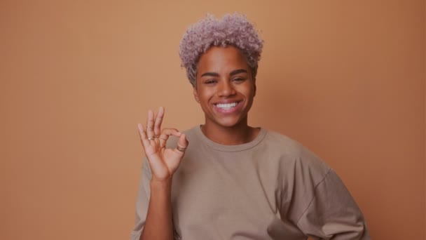 Huvudskott av positiva mörkhyade kvinna med krispigt hår, gör okej gest — Stockvideo