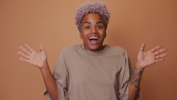 Förvånad afrikansk kvinna hålla munnen öppen sprider händerna över brun bakgrund — Stockvideo