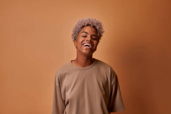 Joven mujer africana sonriendo alegremente mostrando sus dientes blancos sobre la pared beige — Foto de Stock