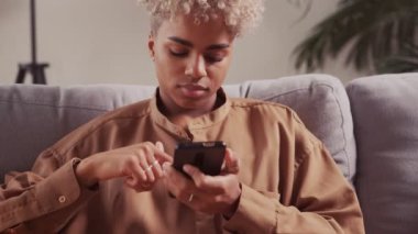 Afrikalı kadınlar kanepede dinlenirken evdeki koltukta akıllı telefon kullanırlar.