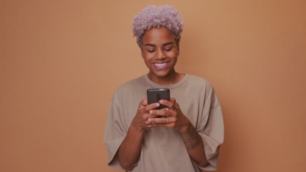 Glimlachende Afrikaanse vrouw types sms-bericht op mobiele telefoon geniet van communicatie — Stockvideo