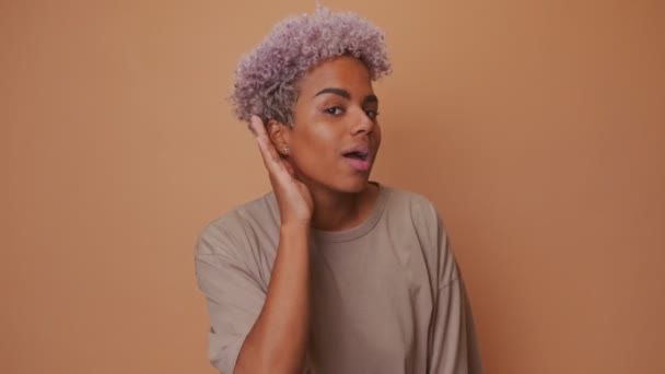 Neugierige junge Afrikanerin mit Hand am Ohr versucht, etwas zu überhören — Stockvideo