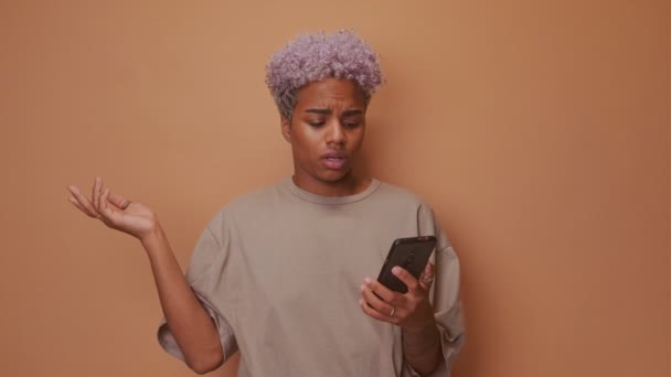 Angry African American young woman holding cellphone irritated by broken device — Stock Video