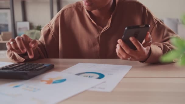 Close up of businesswoman sitting while working on smart phone and calculating. — Stock Video