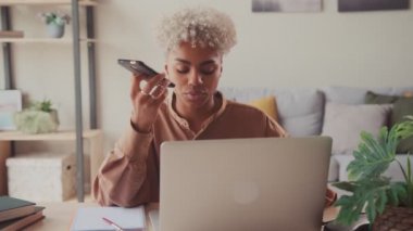 Telefondaki hoparlörde dizüstü bilgisayarı olan odaklanmış kadın çalışan..