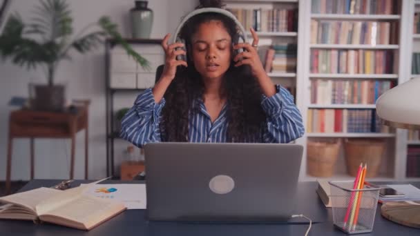 Młoda Indianka zakładająca słuchawki i pracująca na laptopie w biurze — Wideo stockowe