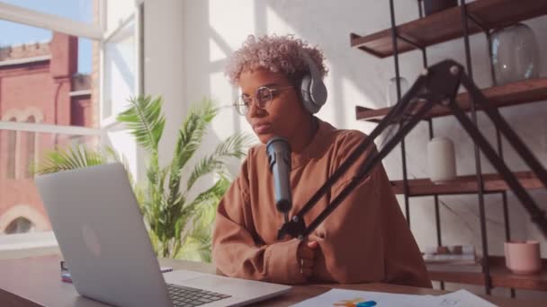 Mujer africana con auriculares saluda a sus seguidores y habla por micrófono — Vídeos de Stock