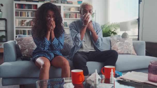 Mezcla de raza joven pareja estornudos narices, que sufren de dolor de cabeza en la sala de estar — Vídeos de Stock