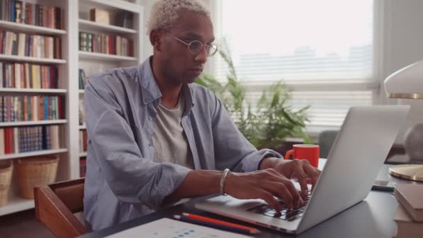 Pensativo hombre africano en el escritorio de la oficina en casa con el ordenador portátil pensando en la inspiración — Vídeo de stock