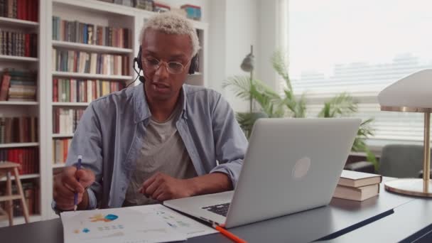 Afrykanin pracujący z laptopem i korzystający z zestawu słuchawkowego podczas spotkania online — Wideo stockowe