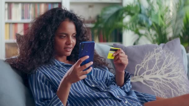 Mulher indiana senta-se no sofá em casa verificar conta bancária on-line via aplicativo móvel — Vídeo de Stock