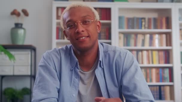 Knappe Afro-Amerikaanse man glimlachend aan het bureau in de woonkamer — Stockvideo