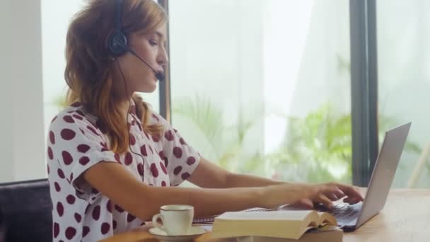 Side View kobieta noszenie słuchawki patrząc na ekranie laptopa rozmowy przez kamerę internetową — Wideo stockowe