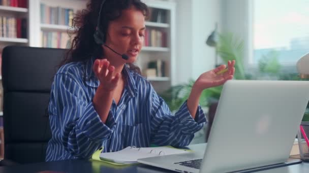 Žena operátorka ve sluchátkách mluví po telefonu, zatímco sedí na svém pracovišti. — Stock video