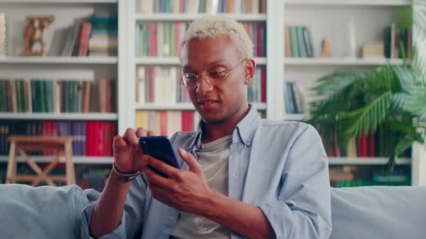 African Man schrijft berichten of bladert door sociale netwerken op moderne mobiele telefoon. — Stockvideo