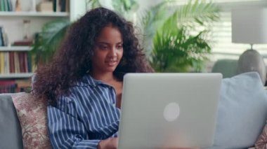 Tatmin olmuş Hintli kadın evdeki rahat koltukta dizüstü bilgisayar kullanıyor..