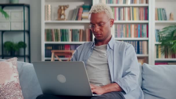 Feliz hombre freelancer que trabaja en línea en el ordenador portátil sentado en casa en el sofá. — Vídeos de Stock