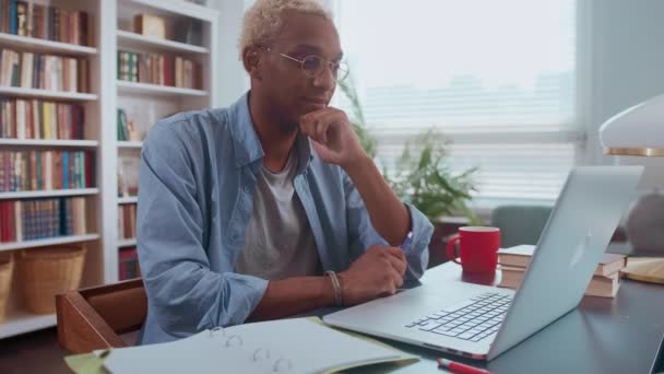 Focado jovem afro-americano usa laptop para estudar em casa. — Vídeo de Stock