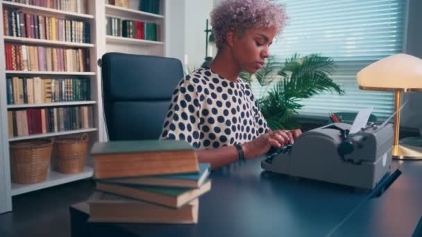 Autora femenina de piel oscura enfocada usando máquina de escribir antigua crea historia interesante. — Vídeos de Stock