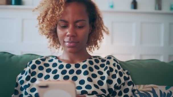 African american woman uses mobile phone to communicate online and browse web. — Stockvideo