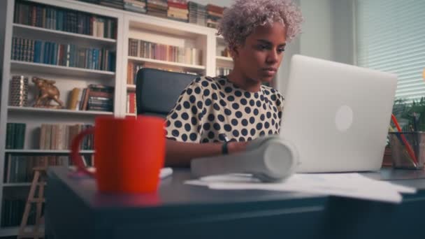 Серйозна темношкіра жінка друкує і відправляє пошту, сидячи в ноутбуці . — стокове відео