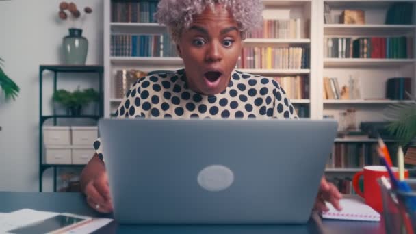 Aufgeregt blickt eine dunkelhäutige Frau auf den Laptop-Bildschirm und kann es kaum glauben. — Stockvideo