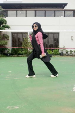 Genç Asyalı tesettürlü Müslüman kadın ve bir torba kahveyle siyah tesettür.