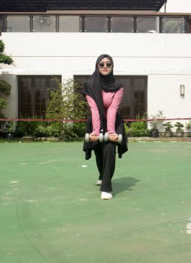 Güzel Müslüman kadın spor salonunda barda egzersiz yapıyor.