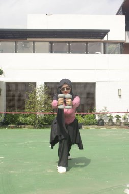 Beyaz elbiseli, siyah elbiseli ve siyah eşarplı bir adam.