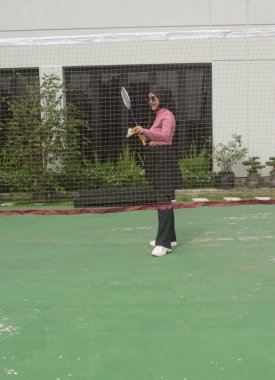 Müslüman kadın parkta badminton oynuyor.