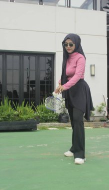 Müslüman kadın parkta badminton oynuyor.