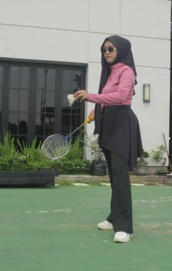 Müslüman kadın parkta badminton oynuyor.