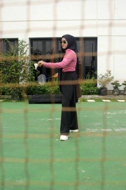 Müslüman kadın parkta badminton oynuyor.