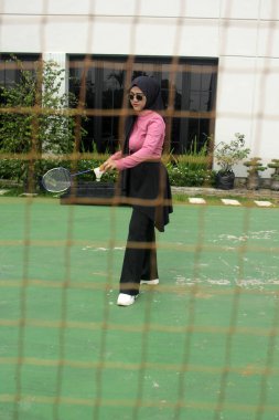 Müslüman kadın parkta badminton oynuyor.