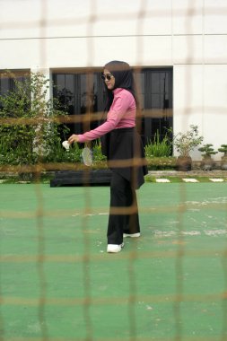 Müslüman kadın parkta badminton oynuyor.