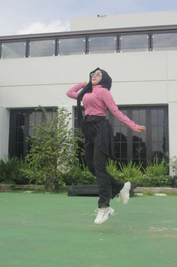 Müslüman kadın parkta badminton oynuyor.