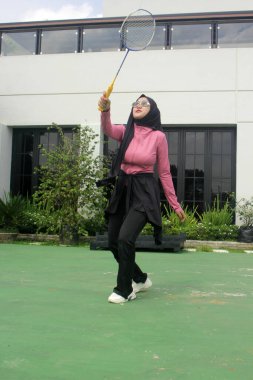 Müslüman kadın parkta badminton oynuyor.