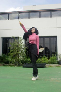 Müslüman kadın parkta badminton oynuyor.