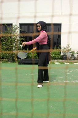 Müslüman kadın parkta badminton oynuyor.