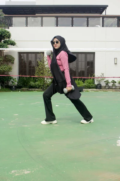 Genç Asyalı tesettürlü Müslüman kadın ve bir torba kahveyle siyah tesettür.