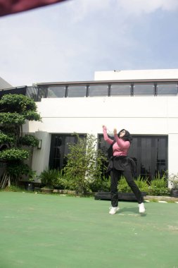 Parkta badminton yapan Asyalı kadın.