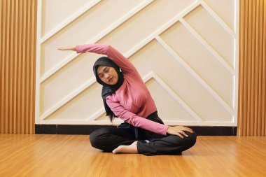 Başörtülü genç Müslüman kadın spor salonunda egzersiz yapıyor..